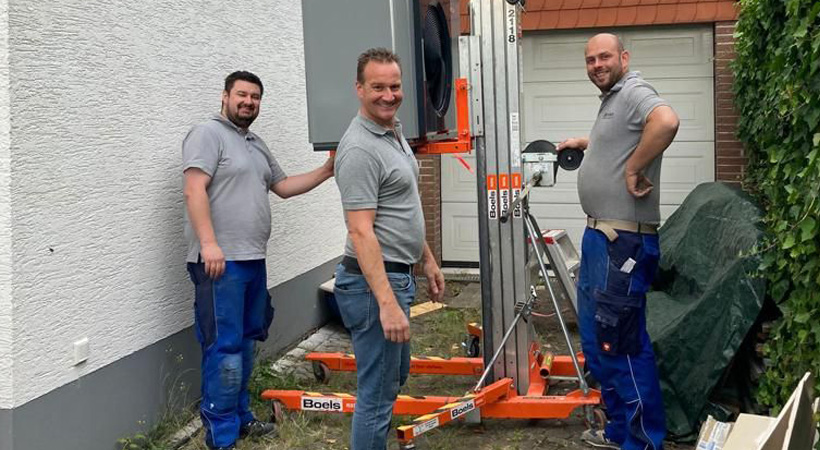 Drei Mitarbeiter auf der Baustelle mit einem Hubwagen.