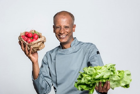 Koch, der Gemüse in der Hand hat