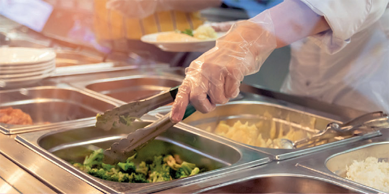 Chef steht hinter Voll-Mittagessen-Tankstelle mit Speisen in Tabletts