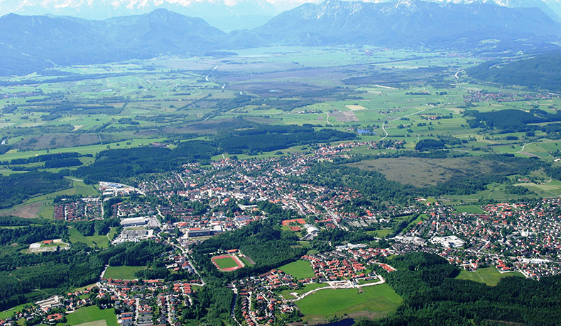 Luftbild von Bad Tölz mit umliegenden Feldern, Wäldern und Alpen im Hintergrund