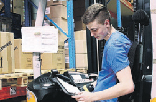 Facharbeiter sitzt auf einem Gabelstapler und überprüft Listen.