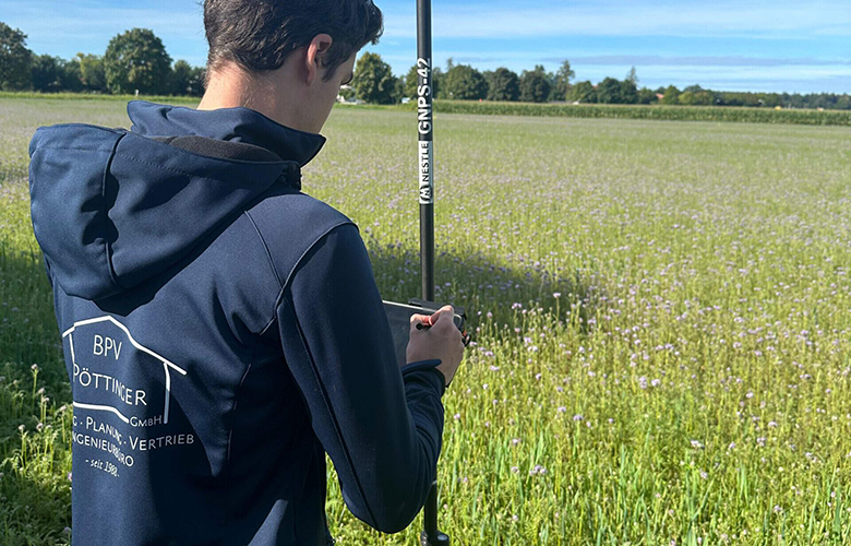Mann in einer dunkelblauen Kapuzenjacke steht auf einem Feld