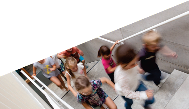 Kinder laufen eine Treppe in einem modernen Gebäude hinauf.