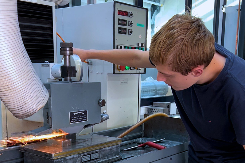 Auszubildender bearbeitet Metall im Schraubstock
