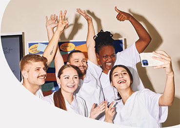 Gruppe junger Pflegekräfte macht lachend ein Selfie