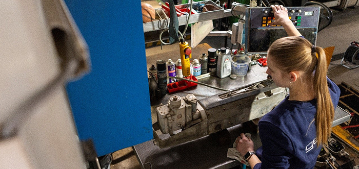 Junge Frau bedient Steuerpult in einer Werkstatt