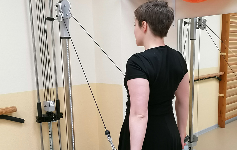 Das Mädchen macht Armübungen mit dem Gerät.