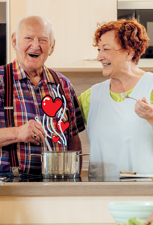 Ein lachendes älteres Paar kocht gemeinsam in einer Küche