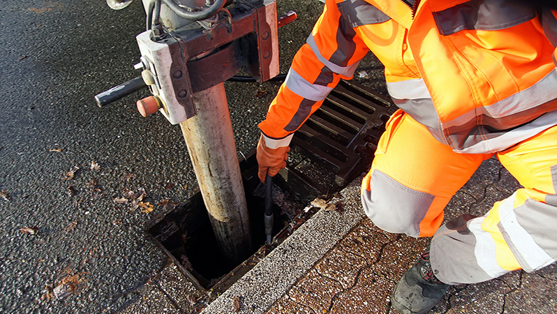 Arbeiter reinigt einen Abwasserkanal.