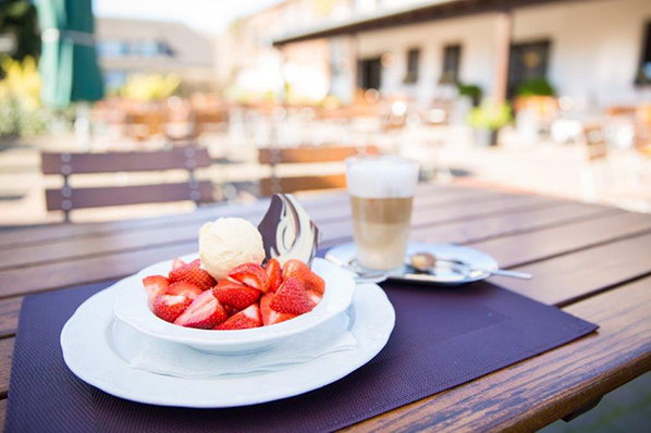 Erdbeeren mit Vanilleeis und Latte Macchiato auf Außenterrasse