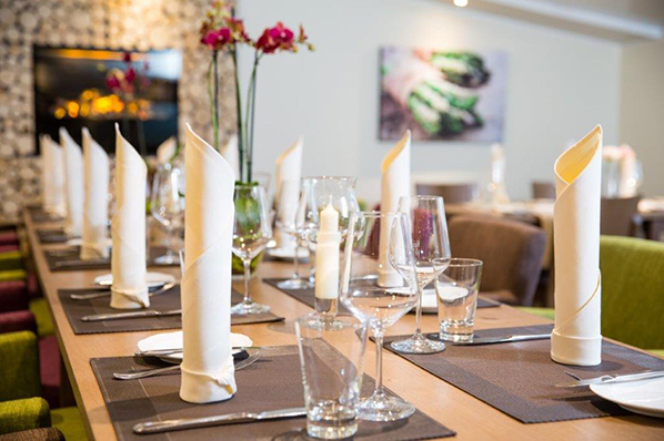 Festlich gedeckter Tisch mit Kerzen, Weingläsern und gefalteten Servietten