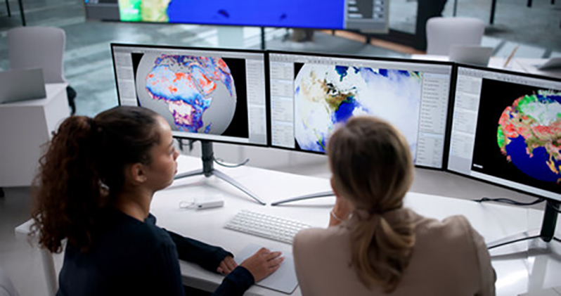 Zwei Frauen analysieren Klimadaten auf großen Monitoren