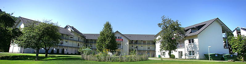Außenansicht eines Gebäudekomplexes mit Balkonen und Gartenanlage