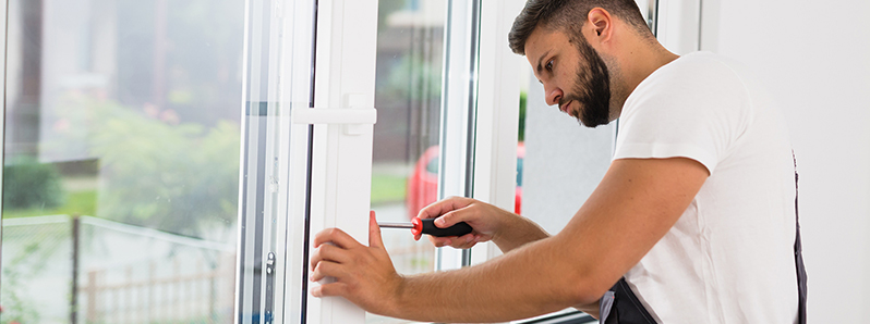 Der Arbeiter im weißen Shirt repariert die Tür.