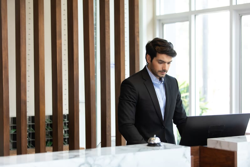 Rezeptionist im Anzug arbeitet konzentriert an einem Computer an einem modernen Empfangstresen