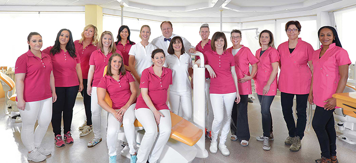 Gruppenfoto eines zahnärztlichen Praxisteams in rosa Oberteilen