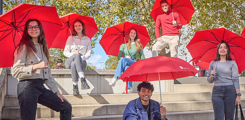 Gruppe Studierender mit roten Regenschirmen