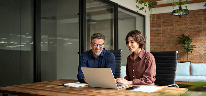 Zwei Personen arbeiten gemeinsam an einem Laptop.