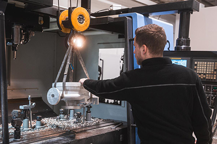 Ein Mann lädt Metallteil mit Kran