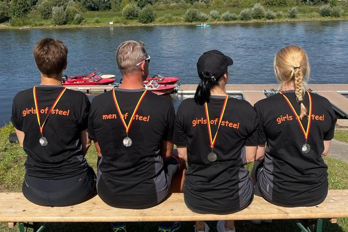 Team mit Medaillen am Wasser