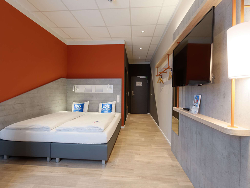 Ein modernes Hotelzimmer enthält ein Doppelbett und einen Fernseher.