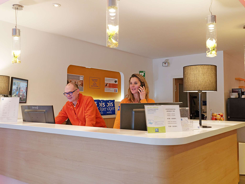 Mitarbeiter stehen an der Rezeption und arbeiten am Computer.