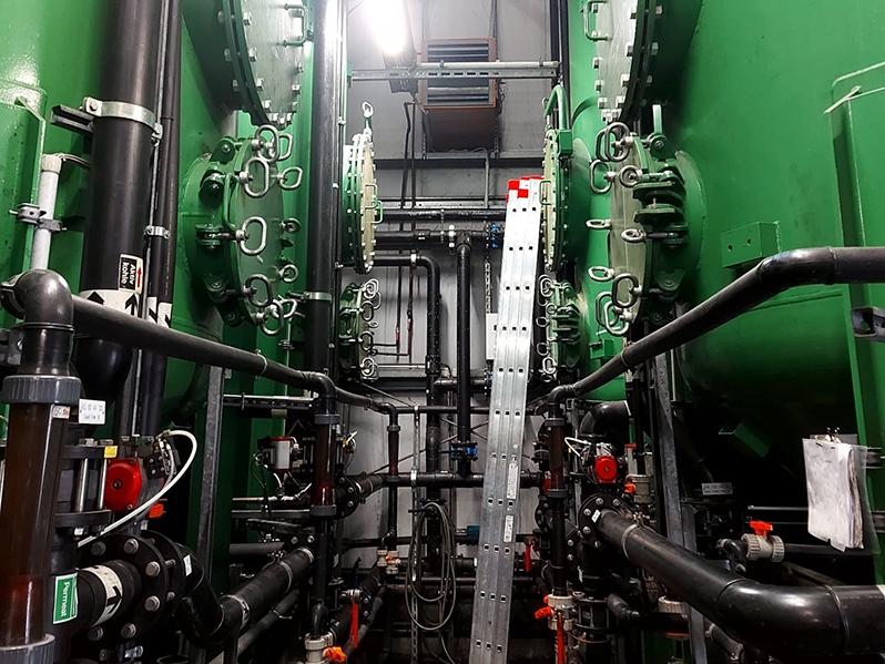 Zwei grüne Tanks mit Rohren in einem Raum