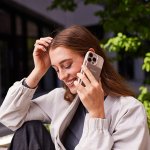 Eine Frau telefoniert lächelnd mit einem Smartphone.