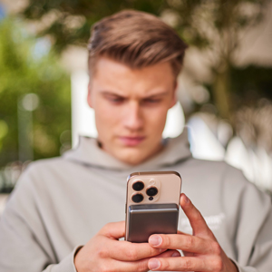 Ein Mann hält ein Smartphone in beiden Händen.