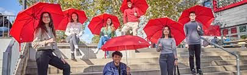 Die Leute stehen mit einem roten Regenschirm auf der Treppe