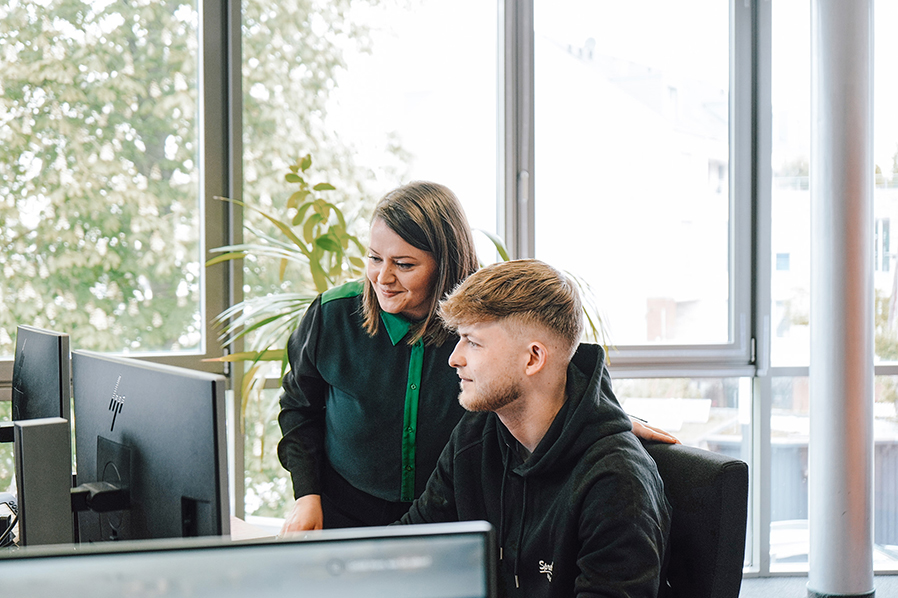 Eine Vorgesetzte berät einen Mitarbeiter am Computer