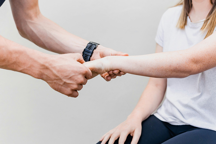 Ein Therapeut untersucht den Arm einer Patientin.
