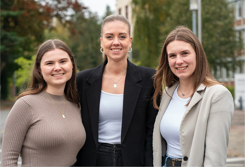 Drei junge Frauen lächeln gemeinsam in die Kamera
