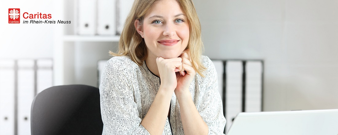 Caritas im Rhein-Kreis Neuss - Lächelnde blonde Frau im Büro