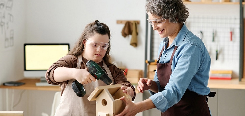 Eine Frau und ein Mädchen bauen ein Holzhaus zusammen