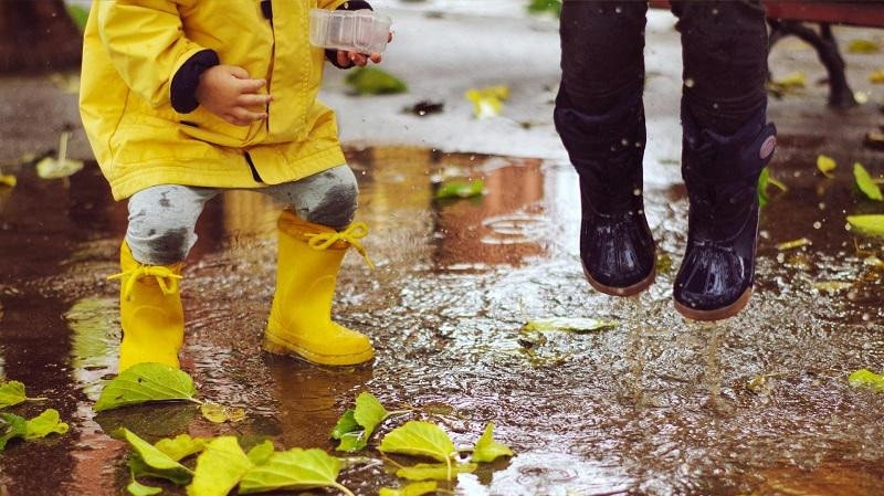 Kinder springen in Pfützen