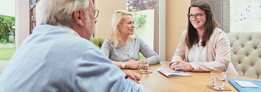 Pflegeberater im Gespräch mit zwei Personen