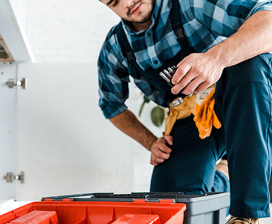 Handwerker greift nach Schraubenschlüsseln.