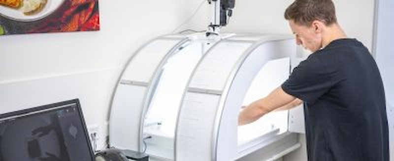 Ein Mann arbeitet mit einem professionellen Lichtscanner zur Produktfotografie oder Qualitätskontrolle.