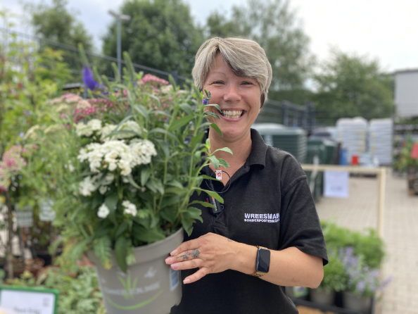Frau hält einen Blumentopf in der Hand und lächelt