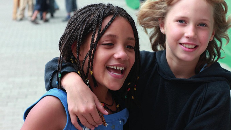 Zwei fröhliche Mädchen umarmen sich und lachen.