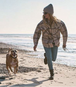 Frau spielt mit Hund am Strand