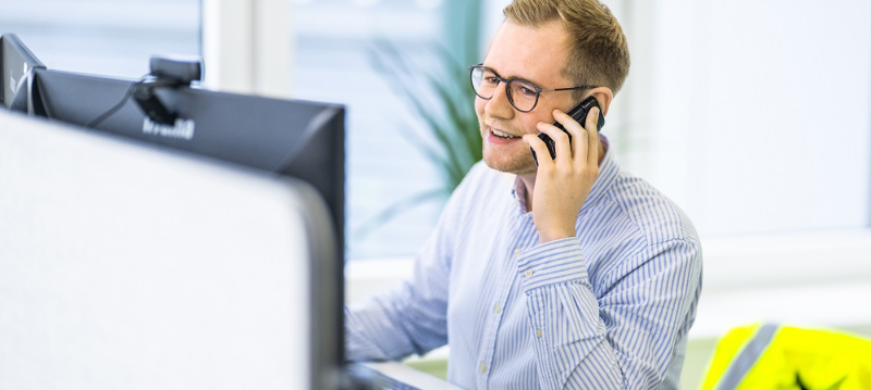 Mann arbeitet am Computer und telefoniert