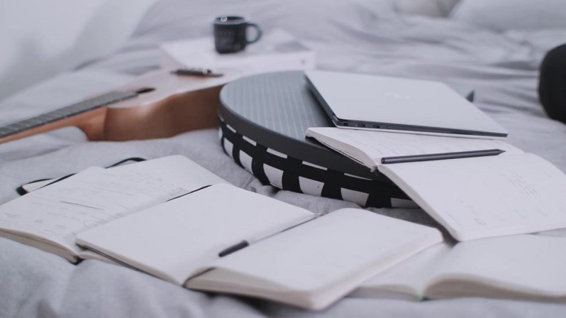 Notizbücher und Laptop auf Bett
