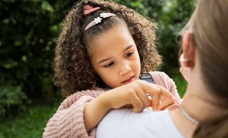 Kleines Mädchen in den Armen einer Frau