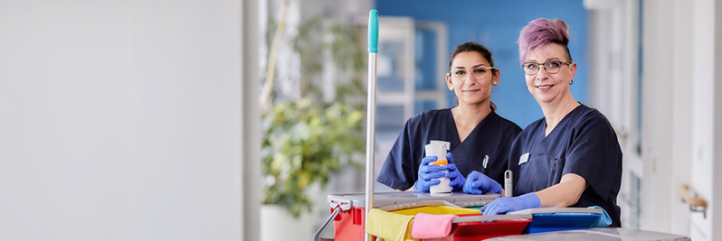 Zwei Reinigungskräfte mit Putzwagen