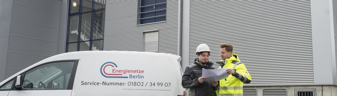 Zwei Arbeiter vor Firmenfahrzeug.