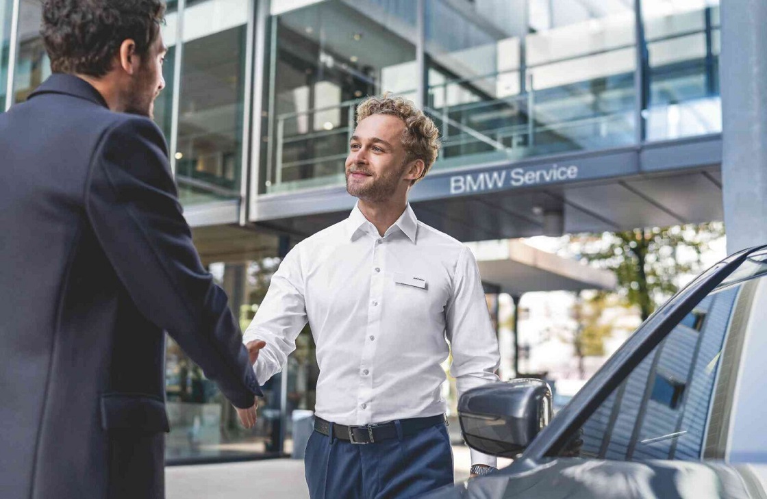 Zwei Männer schütteln sich vor BMW Service die Hand
