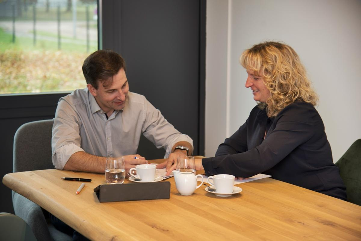 Ein Mann und eine Frau unterhalten sich an einem Holztisch