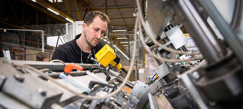 Mann arbeitet an Maschine.